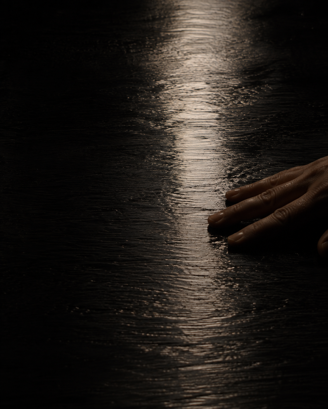 A hand resting on wet lacquer beside a column of reflected window light